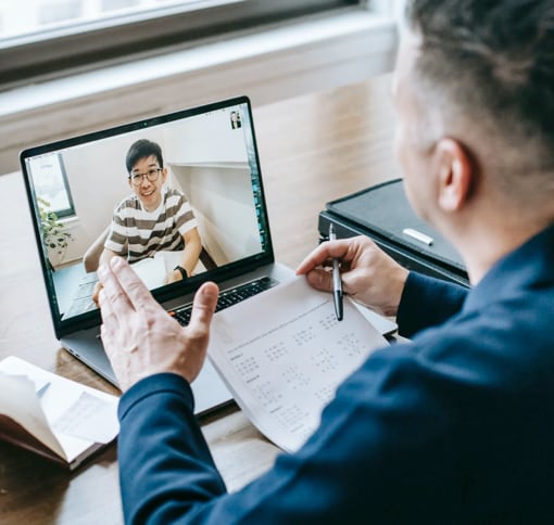 Man sitting in front of a lap top video chatting and taking notes