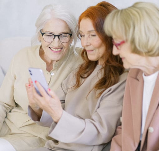 Three ladies looking at phone together talking with a friend